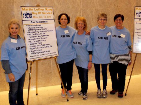 women in blue t-shirts in front of easels with posters