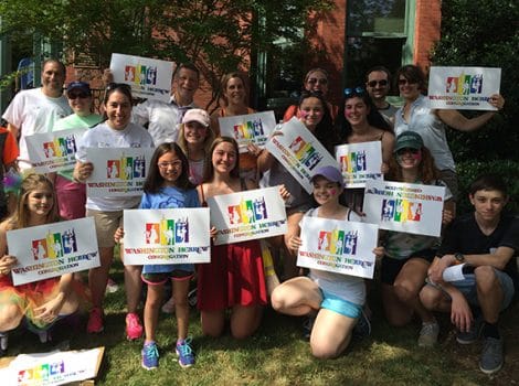 group of people holding rainbow WHC signs