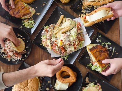 plates of food on a table with hands serving out of some of the dishes