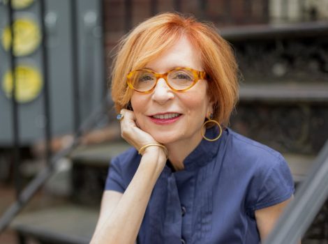 Janet Zalman with hand on chin, sitting on building steps