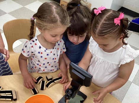 Three young girls look at a leaf through a microscope