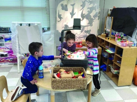 three young children doing shadow play in the classroom