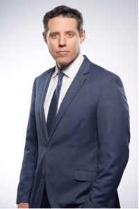 Rick Klein in navy blue suit, white shirt, headshot