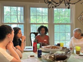 Black and white women sit around a table