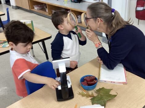 Teacher looks at child through a magnifying glass